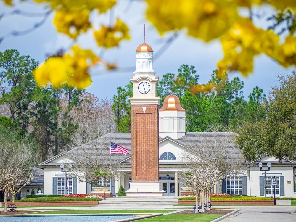 clock tower with overhanging yellow tree and brick building